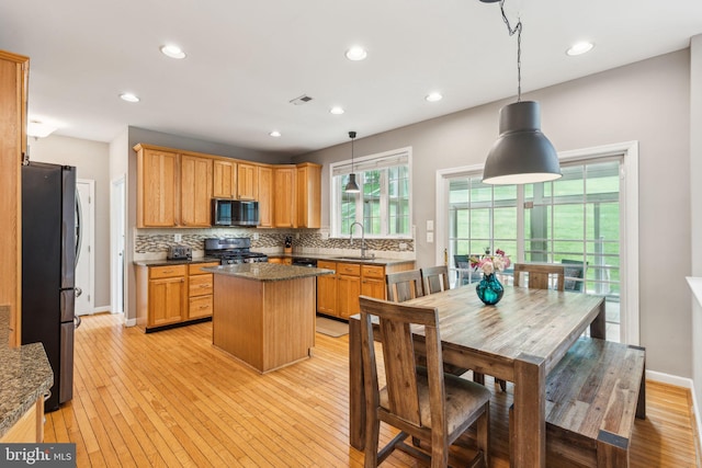 702 Iris Ln, Media, PA 19063 - kitchen featuring appliances with stainless steel finishes, a sink, backsplash, a kitchen island, and light wood-style floors