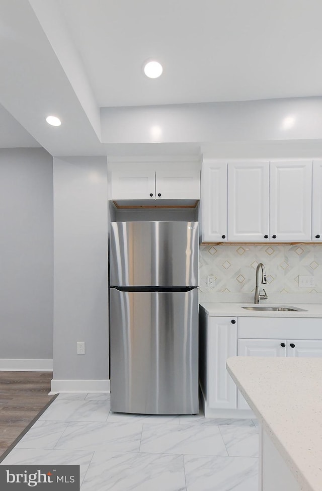 538 N Lakewood Ave, Baltimore, MD 21205 - kitchen with freestanding refrigerator, a sink, baseboards, white cabinets, and backsplash