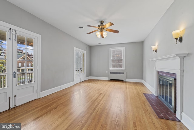 4036 Roland Ave, Baltimore, MD 21211 - unfurnished living room with radiator heating unit, light wood-style flooring, a ceiling fan, baseboards, and a fireplace