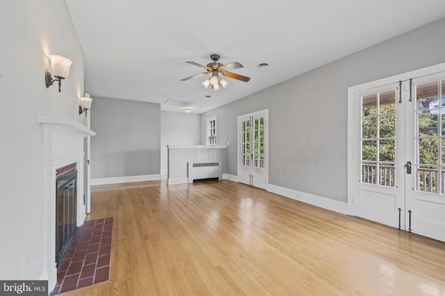 4036 Roland Ave, Baltimore, MD 21211 - unfurnished living room featuring radiator heating unit, a fireplace, light wood-style floors, ceiling fan, and french doors
