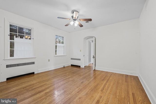 4036 Roland Ave, Baltimore, MD 21211 - empty room with radiator, arched walkways, a ceiling fan, and light wood-style flooring
