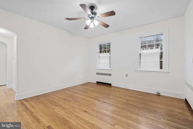 4036 Roland Ave, Baltimore, MD 21211 - spare room featuring radiator heating unit, arched walkways, ceiling fan, light wood-type flooring, and baseboards
