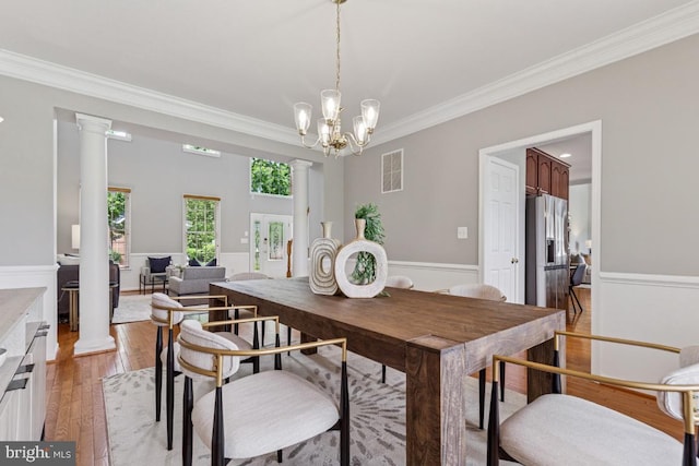 43229 Augustine Pl, Ashburn, VA 20147 - dining space with ornamental molding, light wood-type flooring, ornate columns, a chandelier, and a wainscoted wall