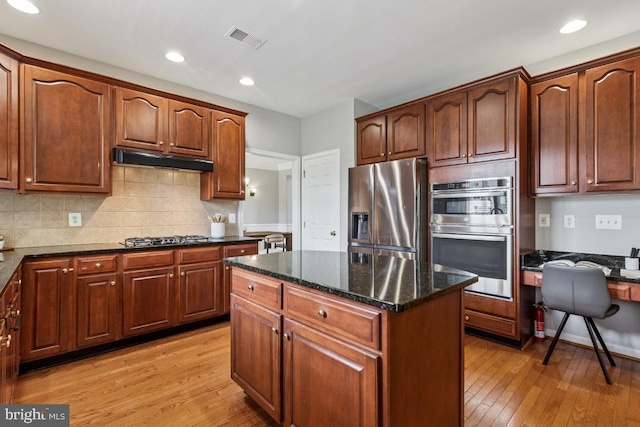 43229 Augustine Pl, Ashburn, VA 20147 - kitchen with stainless steel appliances, light wood finished floors, under cabinet range hood, a kitchen island, and decorative backsplash