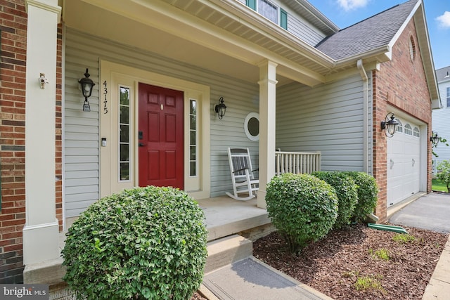 43175 Burstall Ct, Leesburg, VA 20176 - view of exterior entry with covered porch, brick siding, a garage, and a shingled roof