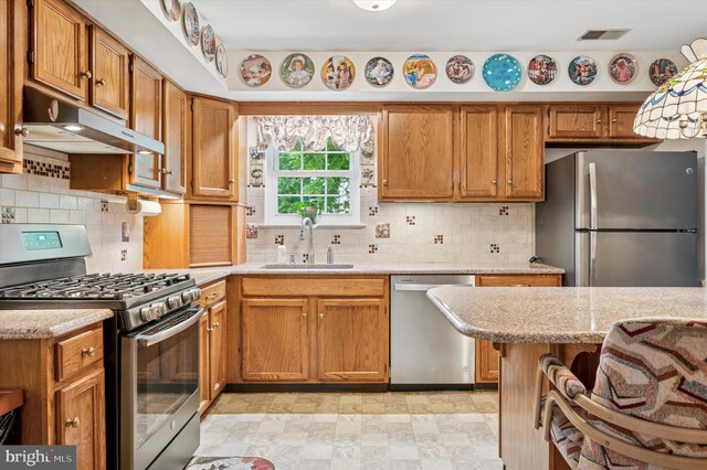 1004 Truman Rd, East Norriton, PA 19403 - kitchen with appliances with stainless steel finishes, a sink, under cabinet range hood, and decorative backsplash