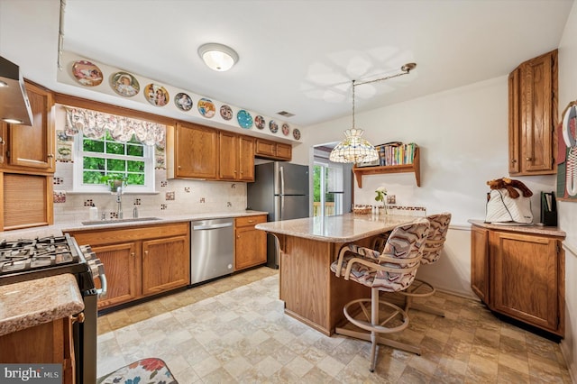 1004 Truman Rd, East Norriton, PA 19403 - kitchen with stainless steel appliances, a sink, a kitchen bar, decorative backsplash, and brown cabinetry