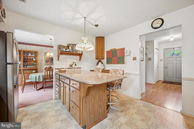 1004 Truman Rd, East Norriton, PA 19403 - kitchen with freestanding refrigerator, a chandelier, light stone counters, pendant lighting, and a center island