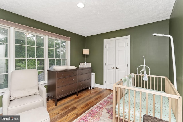 8 Lochwell Ct, Baltimore, MD 21234 - bedroom featuring wood finished floors, a textured ceiling, a closet, a nursery area, and baseboards