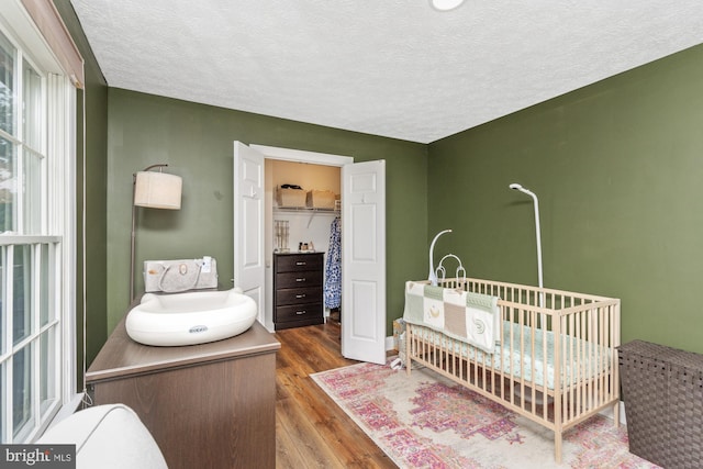 8 Lochwell Ct, Baltimore, MD 21234 - bedroom featuring wood finished floors, a crib, and a textured ceiling