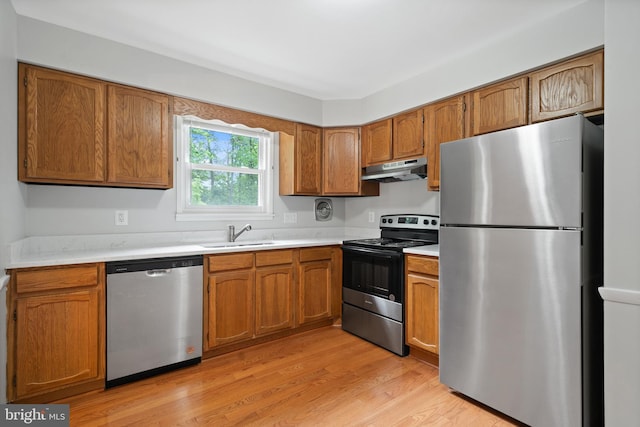 13712 S Springfield Rd, Brandywine, MD 20613 - kitchen with stainless steel appliances, under cabinet range hood, a sink, brown cabinets, and light wood-style flooring