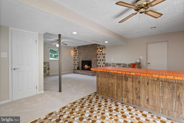 13712 S Springfield Rd, Brandywine, MD 20613 - kitchen featuring a ceiling fan, light carpet, a brick fireplace, tile counters, and a textured ceiling