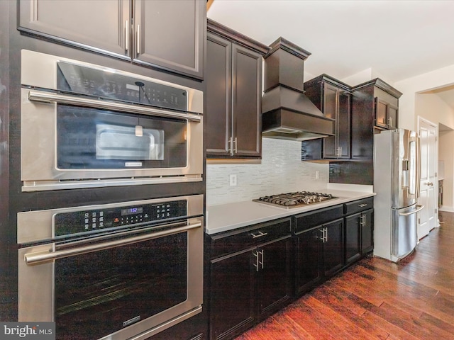 7114 Proclamation Pl, Frederick, MD 21703 - kitchen featuring appliances with stainless steel finishes, custom range hood, dark wood-type flooring, tasteful backsplash, and light countertops