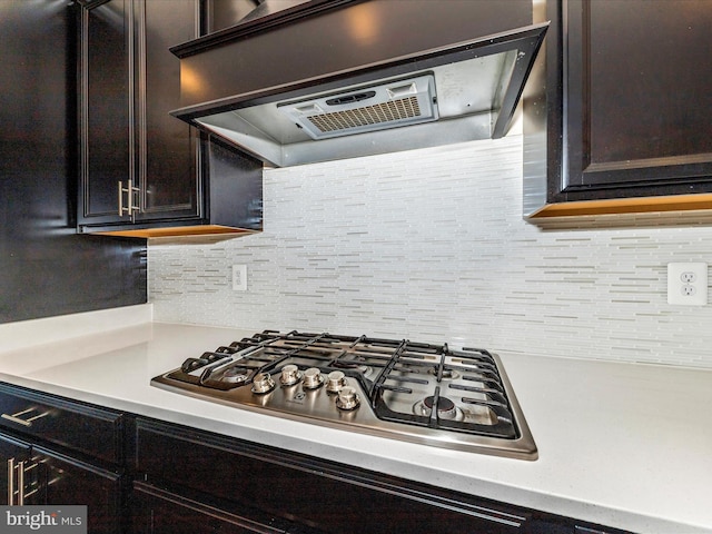 7114 Proclamation Pl, Frederick, MD 21703 - kitchen with ventilation hood, stainless steel gas stovetop, light countertops, dark brown cabinets, and backsplash