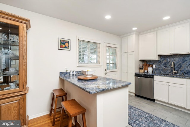 44 Rolling Ln, Hamilton, NJ 08690 - kitchen with dishwasher, a sink, dark stone counters, a breakfast bar, and white cabinets