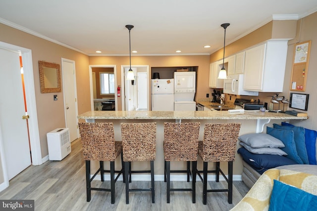 17 139th St Unit 101, Ocean City, MD 21842 - kitchen with white appliances, stacked washing machine and dryer, a peninsula, light wood-type flooring, and light stone countertops
