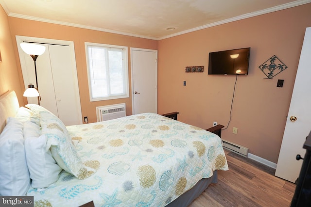 17 139th St Unit 101, Ocean City, MD 21842 - bedroom featuring a baseboard radiator, a wall unit AC, wood finished floors, crown molding, and baseboards