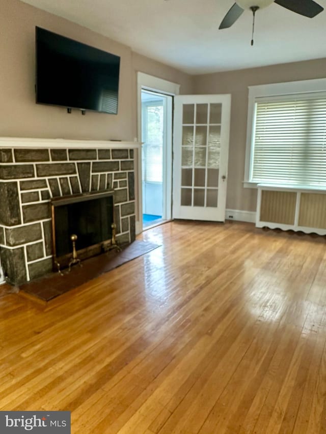 647 Aronimink Pl, Drexel Hill, PA 19026 - unfurnished living room featuring radiator heating unit, a stone fireplace, hardwood / wood-style floors, and healthy amount of natural light