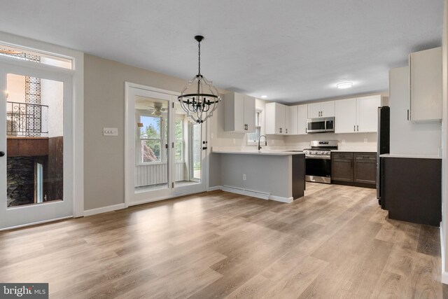 3775 Board Rd, York, PA 17406 - kitchen featuring appliances with stainless steel finishes, a peninsula, a chandelier, light countertops, and light wood-style flooring