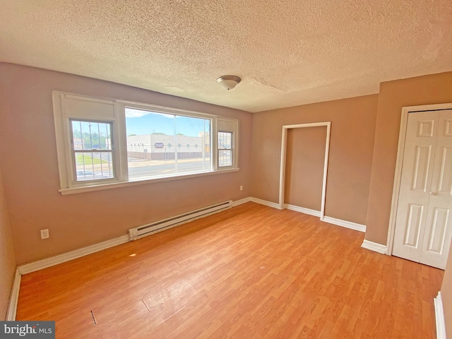 4621 N Broad St, Philadelphia, PA 19140 - unfurnished bedroom featuring a baseboard heating unit, light wood-style floors, baseboards, and a textured ceiling