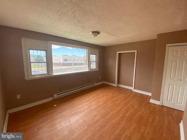 4621 N Broad St, Philadelphia, PA 19140 - unfurnished bedroom with a baseboard radiator, light wood-style flooring, a textured ceiling, and baseboards