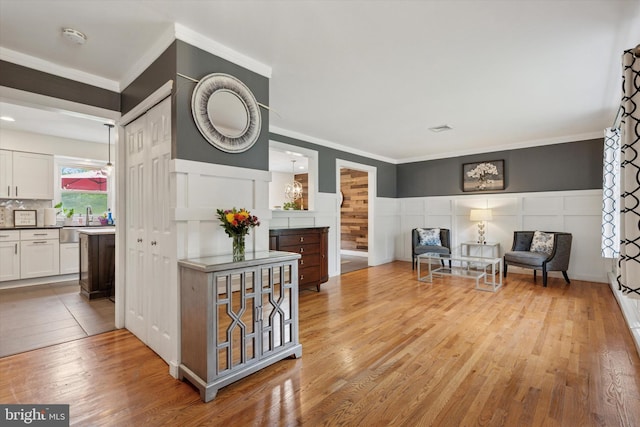 4811 Kings Rd, Doylestown, PA 18902 - living area featuring light wood-style flooring, crown molding, a wainscoted wall, and a decorative wall