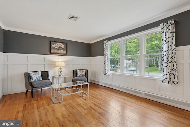 4811 Kings Rd, Doylestown, PA 18902 - living area with a decorative wall, crown molding, a wainscoted wall, wood finished floors, and a baseboard heating unit