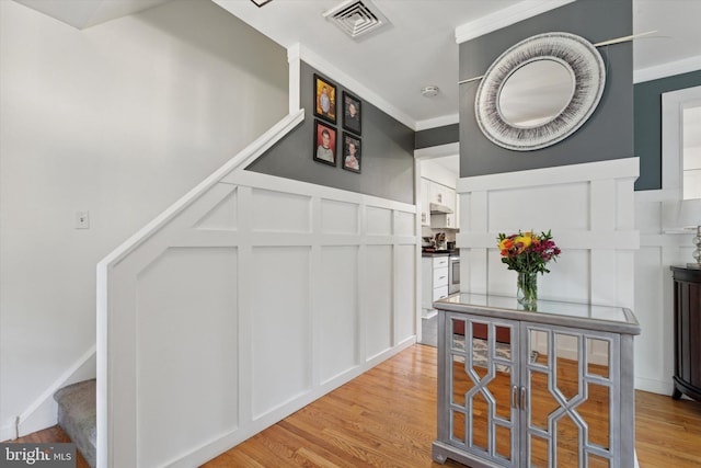 4811 Kings Rd, Doylestown, PA 18902 - hall featuring a decorative wall, stairs, light wood finished floors, crown molding, and wainscoting