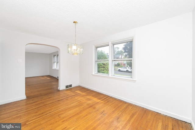 681 Dutton Cir, Springfield, PA 19064 - unfurnished room with arched walkways, a chandelier, light wood-style floors, baseboards, and a textured ceiling