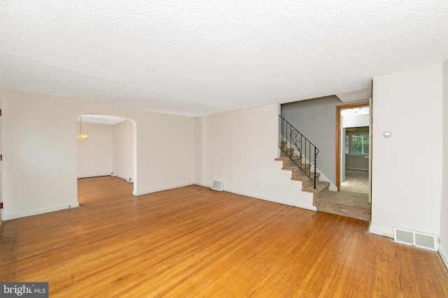 681 Dutton Cir, Springfield, PA 19064 - spare room featuring light wood-style floors, a textured ceiling, stairs, arched walkways, and baseboards