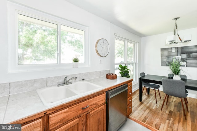 6322 Phyllis Ln, Alexandria, VA 22312 - kitchen featuring dishwasher, a sink, brown cabinetry, light countertops, and pendant lighting