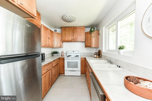 6322 Phyllis Ln, Alexandria, VA 22312 - kitchen with appliances with stainless steel finishes, a sink, brown cabinets, tile counters, and light tile patterned floors