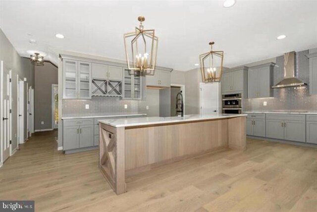 2306 Monticello Rd, Baltimore, MD 21216 - kitchen featuring wall chimney exhaust hood, gray cabinetry, stainless steel double oven, a chandelier, and tasteful backsplash