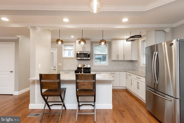 2306 Monticello Rd, Baltimore, MD 21216 - kitchen with stainless steel appliances, light wood-type flooring, a center island, white cabinets, and backsplash