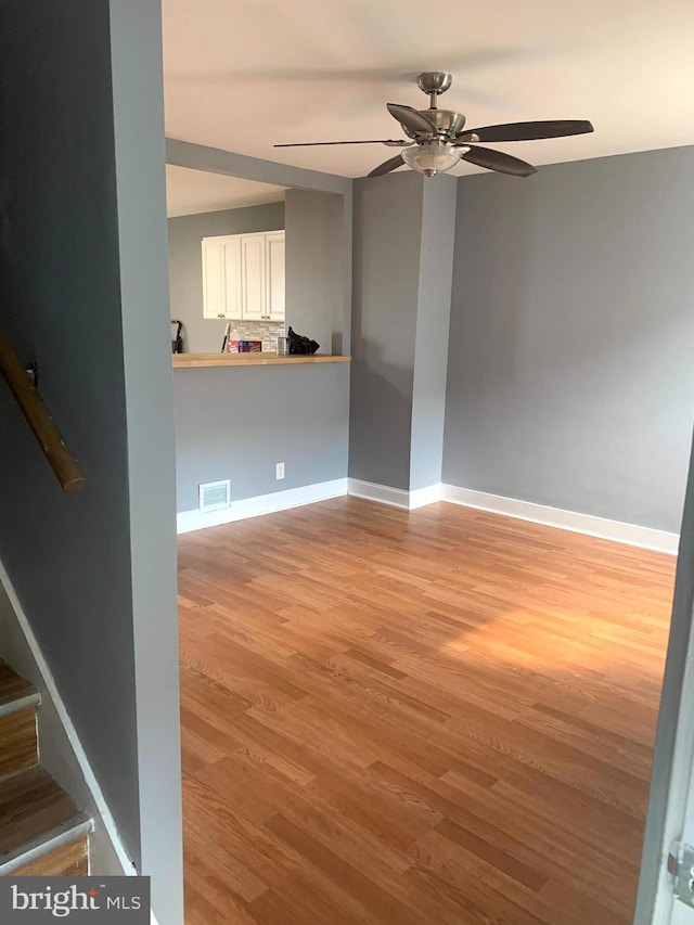 4103 Grace Ct, Baltimore City, MD 21226 - empty room with light wood-style flooring, ceiling fan, baseboards, and stairs