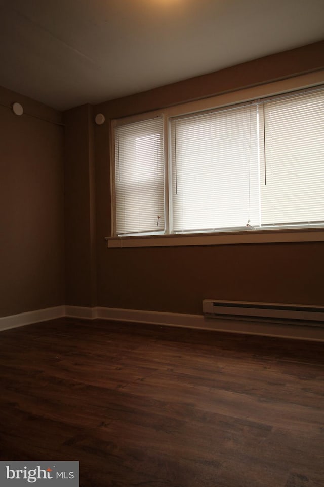 4623 N Broad St, Philadelphia, PA 19140 - spare room with a baseboard radiator, dark wood-style floors, and baseboards