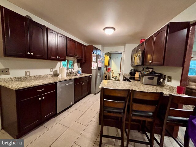 149 Smoketown Rd, Mertztown, PA 19539 - kitchen featuring stainless steel appliances, a peninsula, a sink, a kitchen bar, and light stone counters