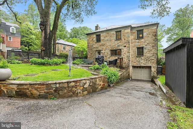 715 Morningside Dr, Towson, MD 21204 - rear view of house featuring stone siding, asphalt driveway, a chimney, and a garage