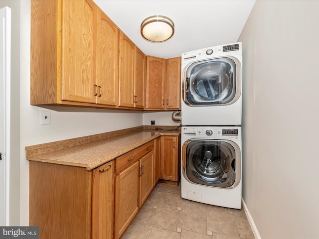 21 E D St, Brunswick, MD 21716 - washroom featuring estacked washer and dryer, cabinet space, light tile patterned floors, and baseboards