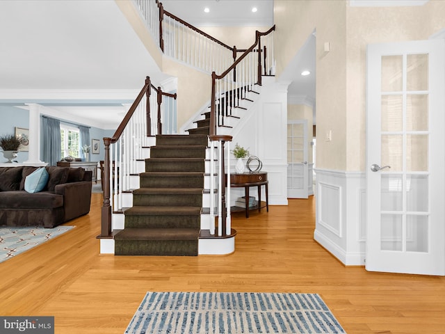 116 Colony Xing, Edgewater, MD 21037 - staircase featuring ornamental molding, wood finished floors, a towering ceiling, a decorative wall, and wainscoting