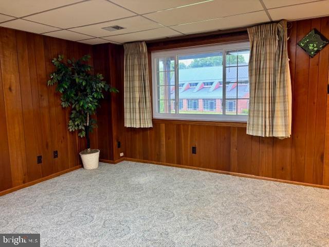 132 Popodickon Dr, Boyertown, PA 19512 - empty room with a drop ceiling, carpet floors, wooden walls, and baseboards