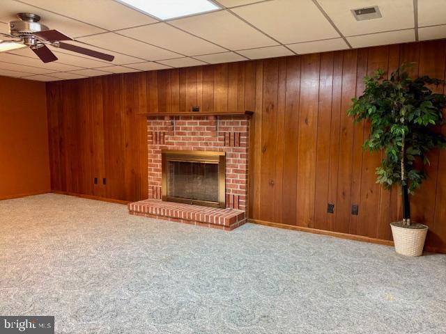 132 Popodickon Dr, Boyertown, PA 19512 - unfurnished living room with a ceiling fan, a paneled ceiling, carpet flooring, a fireplace, and wood walls