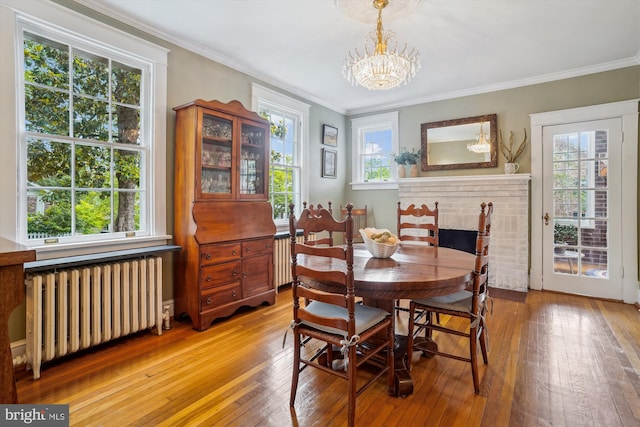 402 W Masonic View Ave, Alexandria, VA 22301 - dining room featuring radiator heating unit, light wood-style floors, a chandelier, crown molding, and a brick fireplace