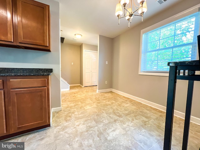 131 Arundel Rd, Pasadena, MD 21122 - kitchen with brown cabinetry, a chandelier, dark stone countertops, baseboards, and pendant lighting