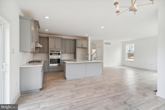 4338 Taviston Ct E, Emmaus, PA 18049 - kitchen with gray cabinetry, stainless steel appliances, under cabinet range hood, light countertops, and baseboards