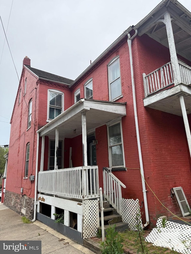 567 S Christian St, Lancaster, PA 17602 - view of property featuring a balcony, brick siding, a porch, and a chimney