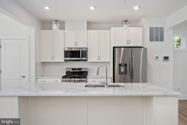 7404 Rocky Creek Ter, Annandale, VA 22003 - kitchen featuring stainless steel appliances, a sink, a kitchen island with sink, white cabinets, and backsplash