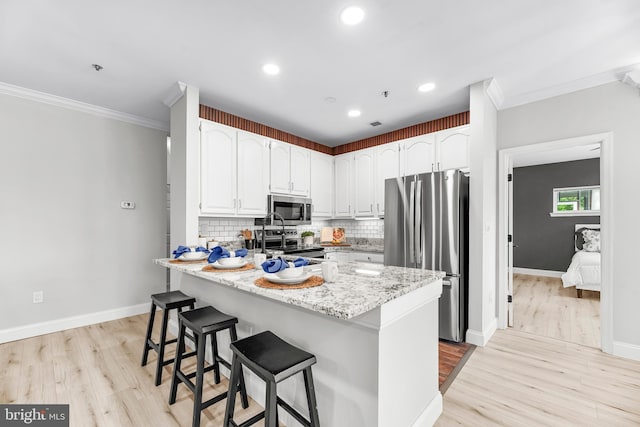 1104 Back Creek Loop Unit 1104, Solomons, MD 20688 - kitchen featuring stainless steel appliances, ornamental molding, a kitchen breakfast bar, tasteful backsplash, and white cabinetry