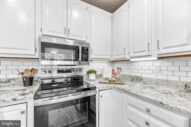 1104 Back Creek Loop Unit 1104, Solomons, MD 20688 - kitchen featuring appliances with stainless steel finishes, white cabinets, decorative backsplash, and light stone countertops