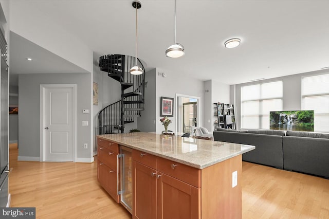 2425 L St NW Unit 623, Washington, DC 20037 - kitchen featuring beverage cooler, light wood-style floors, light stone countertops, decorative light fixtures, and brown cabinetry